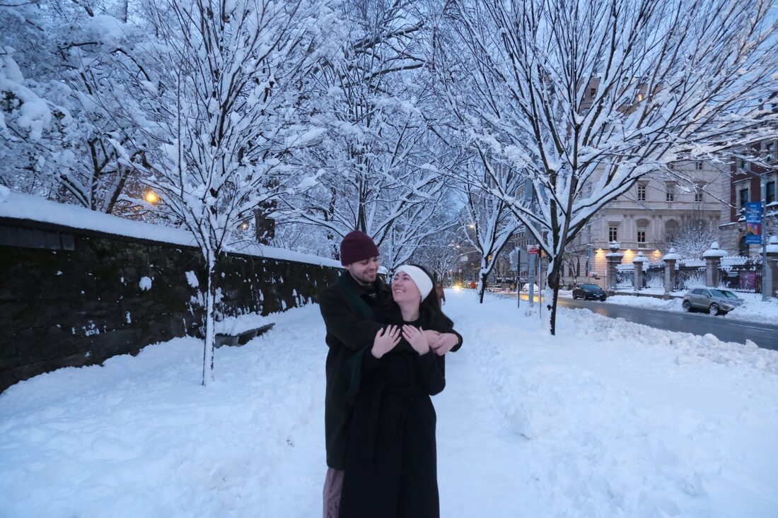 Katrina and Matthew embracing on a snowy city street at dusk